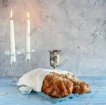 Challah under challah cover, candles lit and silver kiddush cup