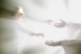 A girl floating in a ray of light reaching out to God's hands