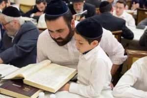 A boy learning Gemara with his father in a Beit Midrash
