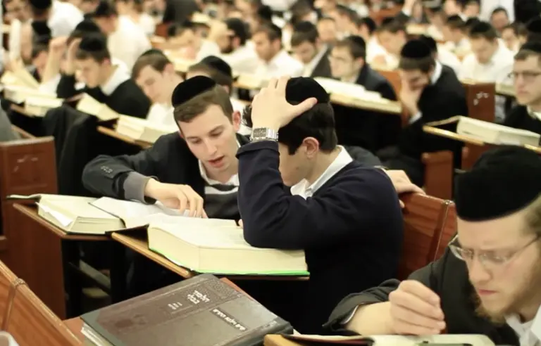 Two Yeshiva boys wearing black suits learning together in the Beit Midrash