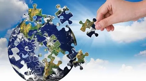 A hand putting together the world in te shape of a puzzle