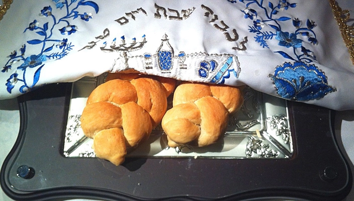 Two Challah's on a cutting board under the challah cover