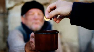 Man giving a coin to a poor man holding out a brown mug