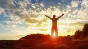Man standing high with is arms open as the sun is setting