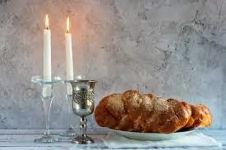 Shabbat table with lit candles, a braided challah and a kiddush cup