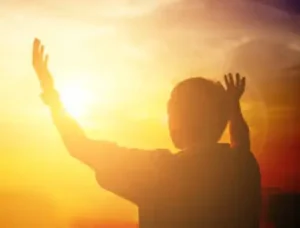 Boy throwing his hands in the air whole staring at the sun set