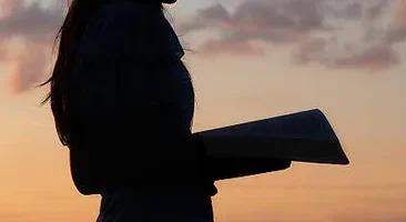 Woman praying as the sun is setting by the beach