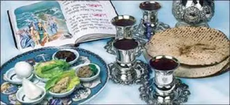 Picture of Seder table- Hagadah, four cups of wine, matzah, seder plate