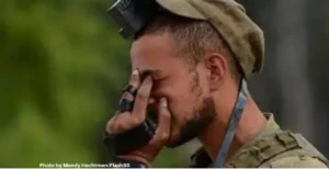 IDF soldier in uniform davening with teffilin on