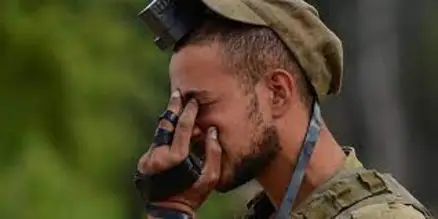 IDF soldier in uniform davening with teffilin on