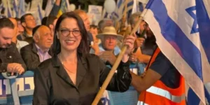Galit Distel holding Israeli flag in front of a crowd