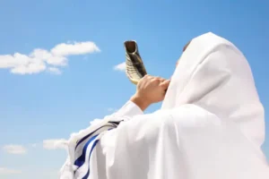 Man wearing a tallit blowing shofar outside
